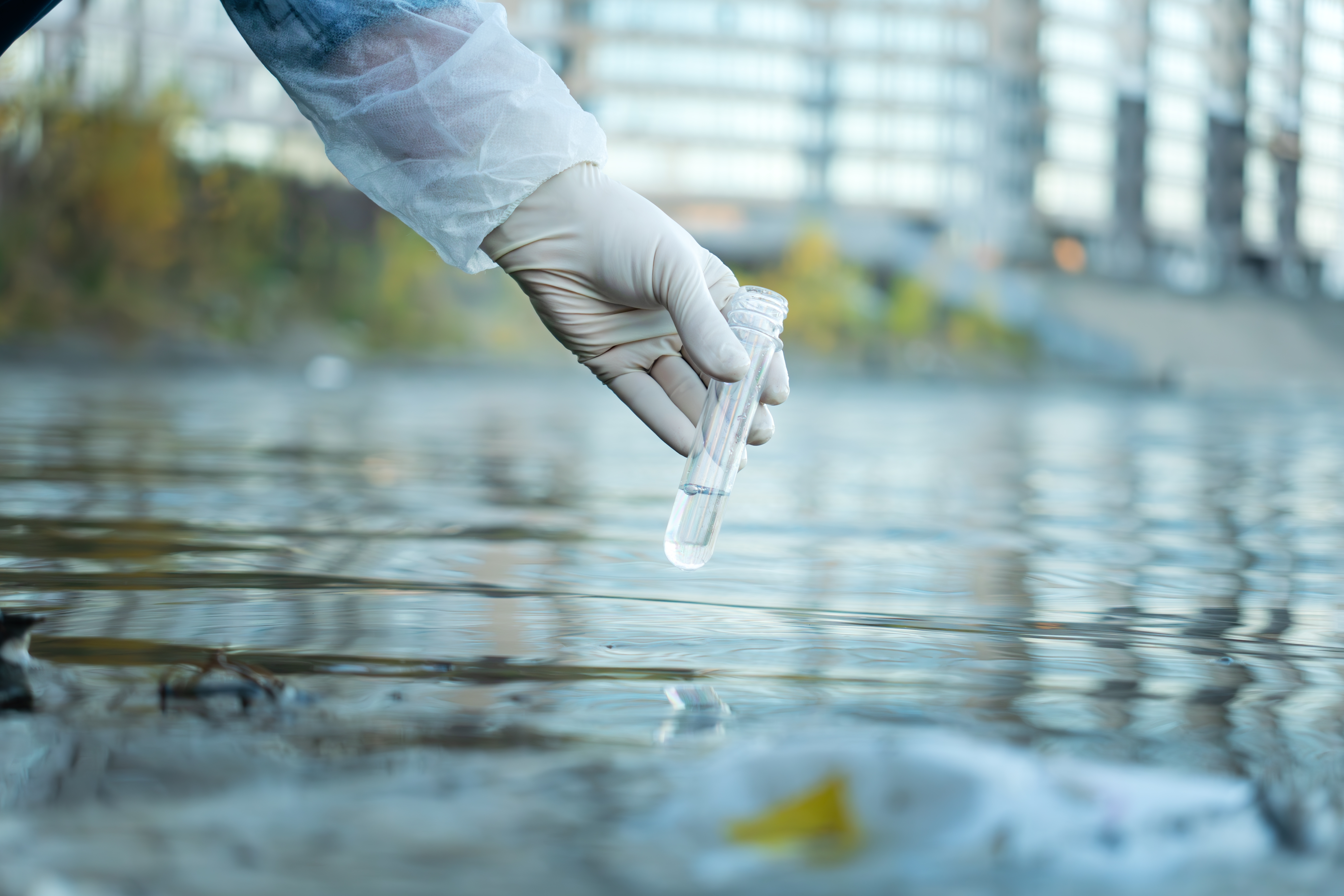 Close up of scientist with white glove holding test tube with water