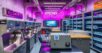 A lab containing different metal structures and individual work stations is illuminated in pink light.